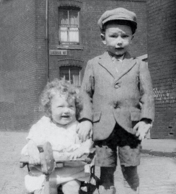 Restored black and white image of brother and sister on terraced street