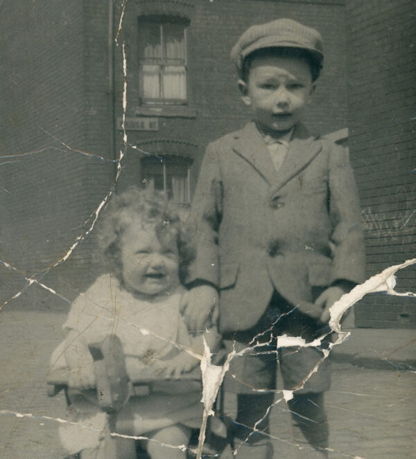 Damaged black and white image of brother and sister on terraced street